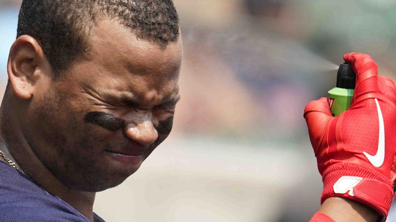 A Red Sox baseball player applies sunscreen to his face during an MLB game. (AP)